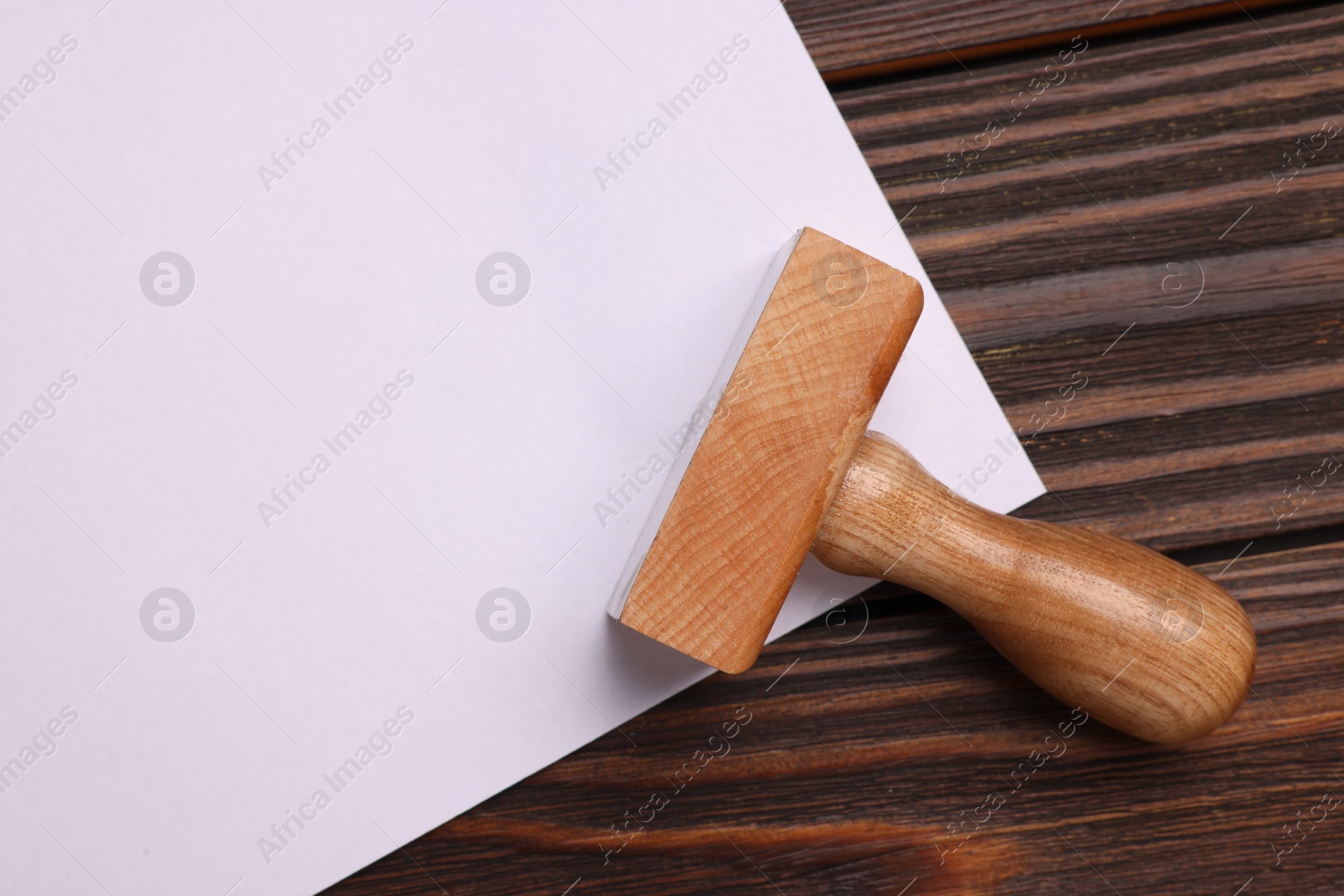 Photo of One stamp tool and sheet of paper on wooden table, top view. Space for text