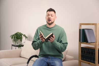 Photo of Man with book suffering from dust allergy at home