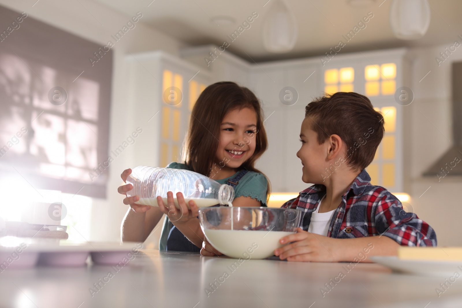 Photo of Cute little children cooking dough in kitchen at home