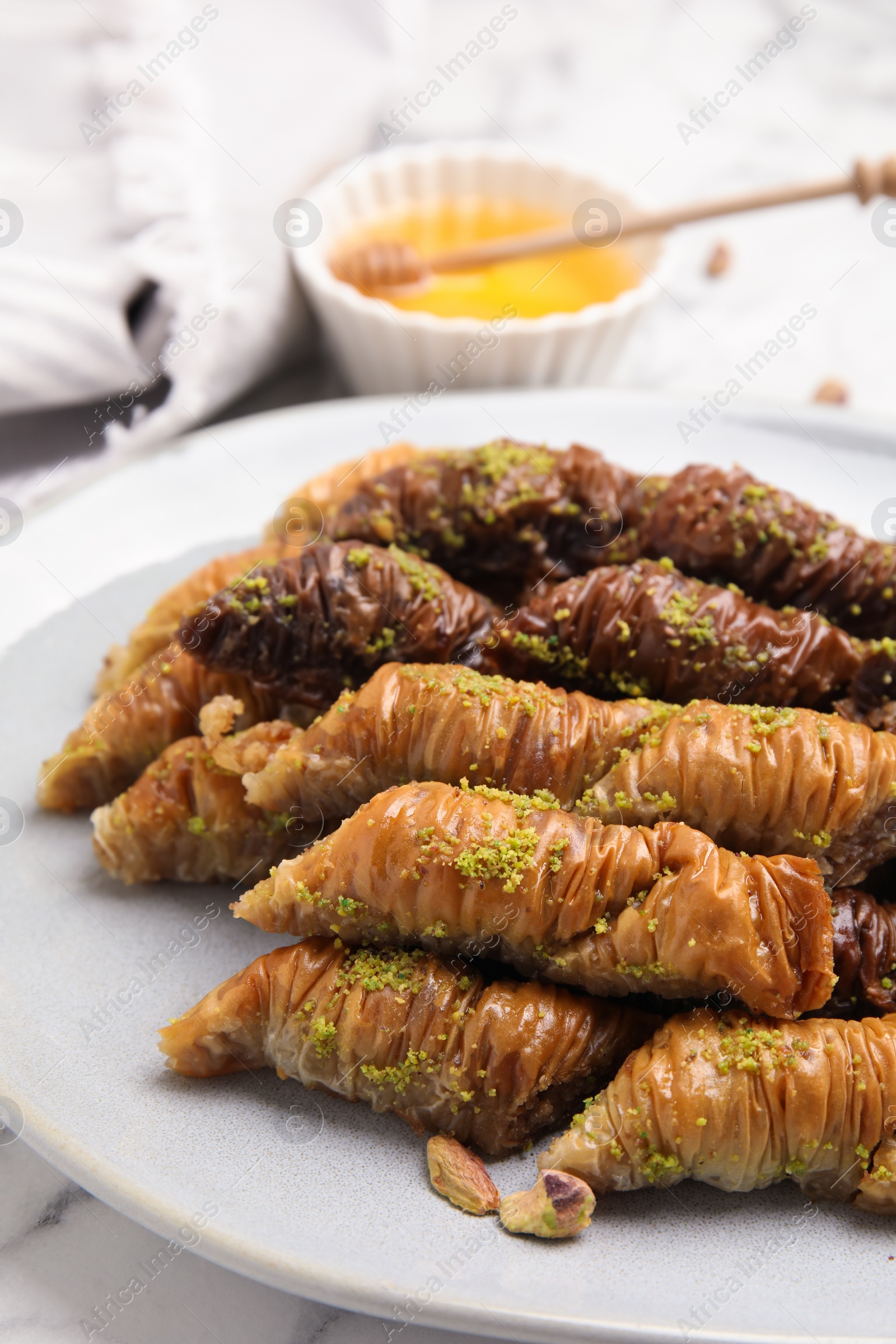 Photo of Delicious baklava with pistachio nuts on white marble table, closeup