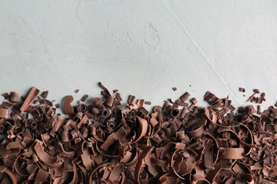 Chocolate curls and space for text on gray background, top view