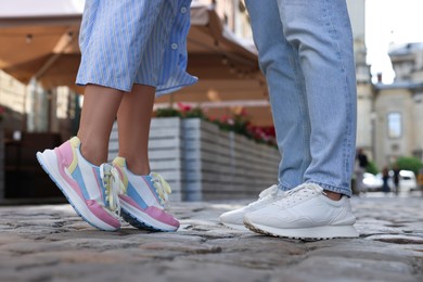 Photo of Woman and man wearing stylish sneakers on city street, closeup