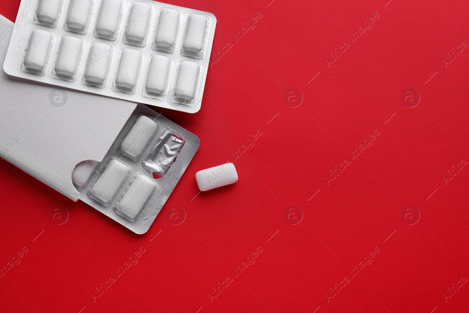 Photo of Blisters with chewing gums on red background, flat lay. Space for text