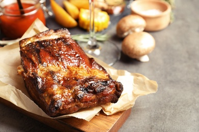 Photo of Piece of delicious barbecued ribs served on gray table
