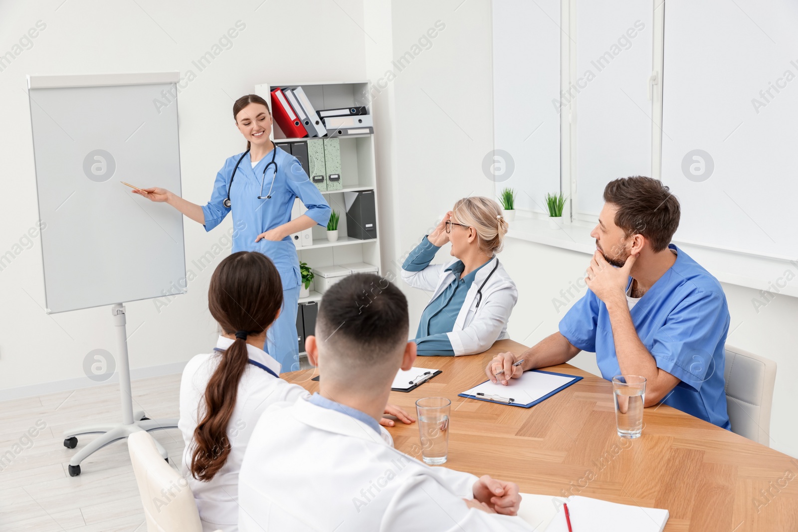 Photo of Doctor giving lecture near flipchart in conference room