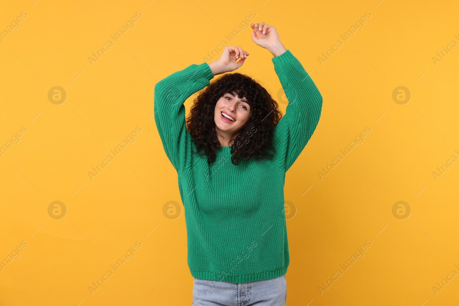 Photo of Happy young woman in stylish green sweater on yellow background