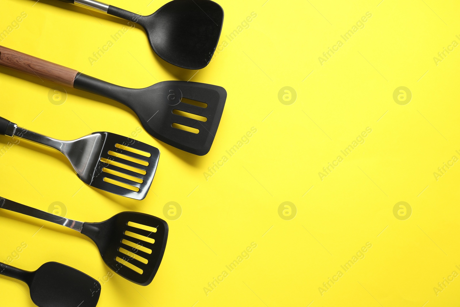 Photo of Different spatulas on yellow background, flat lay. Space for text