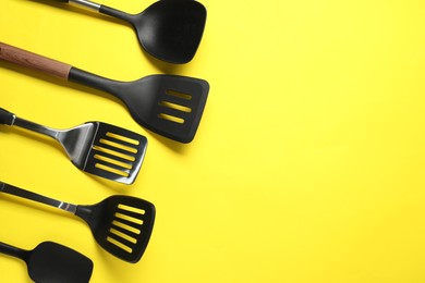 Photo of Different spatulas on yellow background, flat lay. Space for text