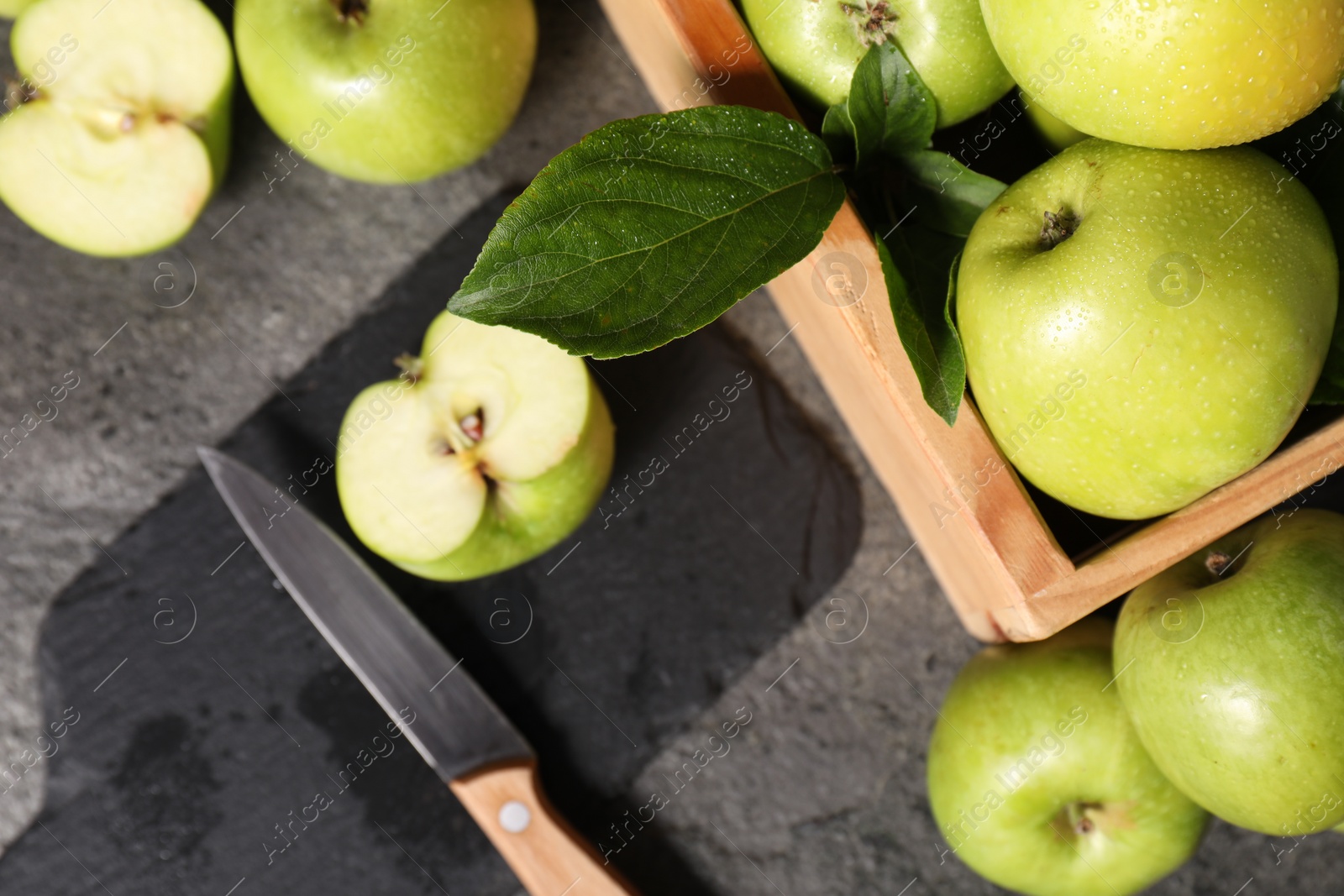 Photo of Ripe green apples, cutting board and knife on grey table, flat lay