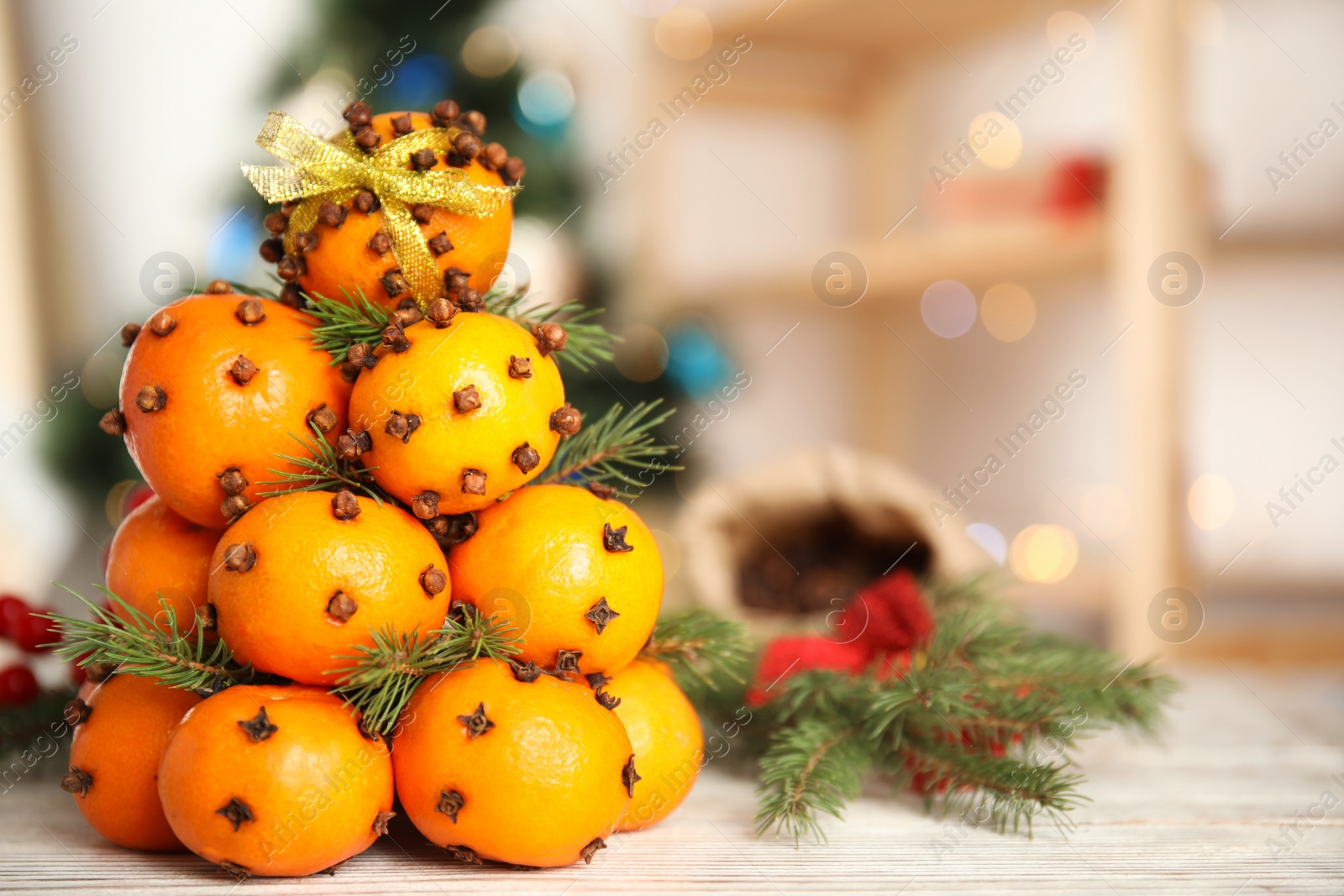 Photo of Pomander balls made of tangerines with cloves and fir branches on white wooden table, space for text