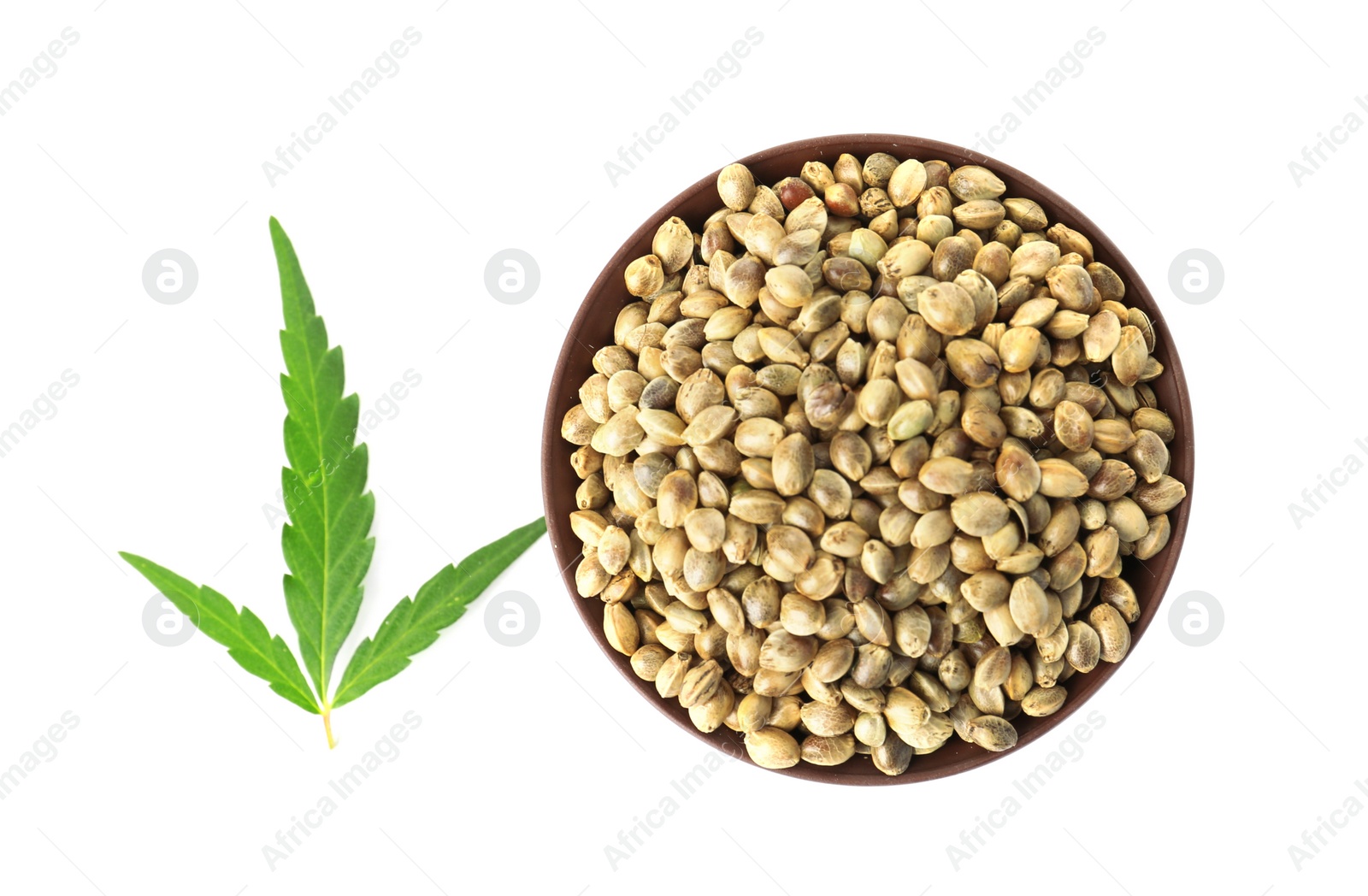 Photo of Bowl of hemp seeds with green leaf on white background, top view