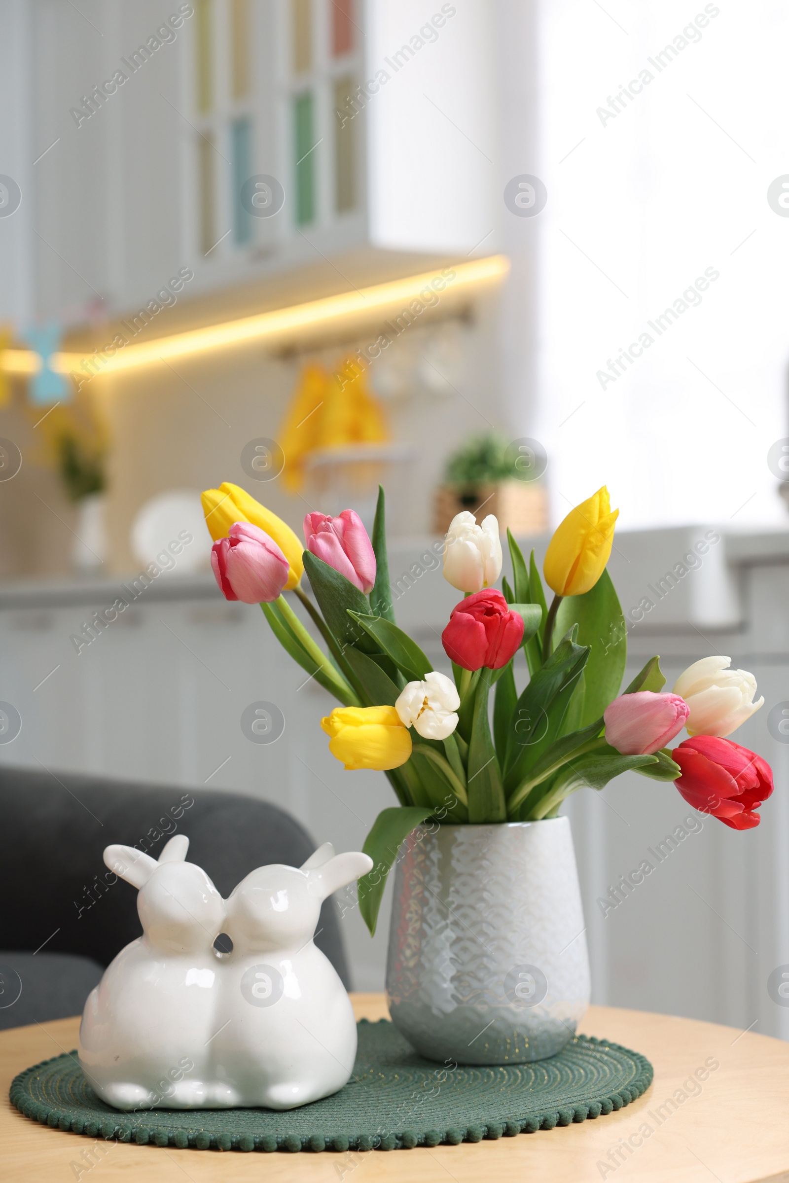 Photo of Easter decorations. Bouquet of tulips and bunny figures on table indoors