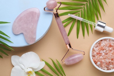 Flat lay composition with gua sha stone and face roller on beige background