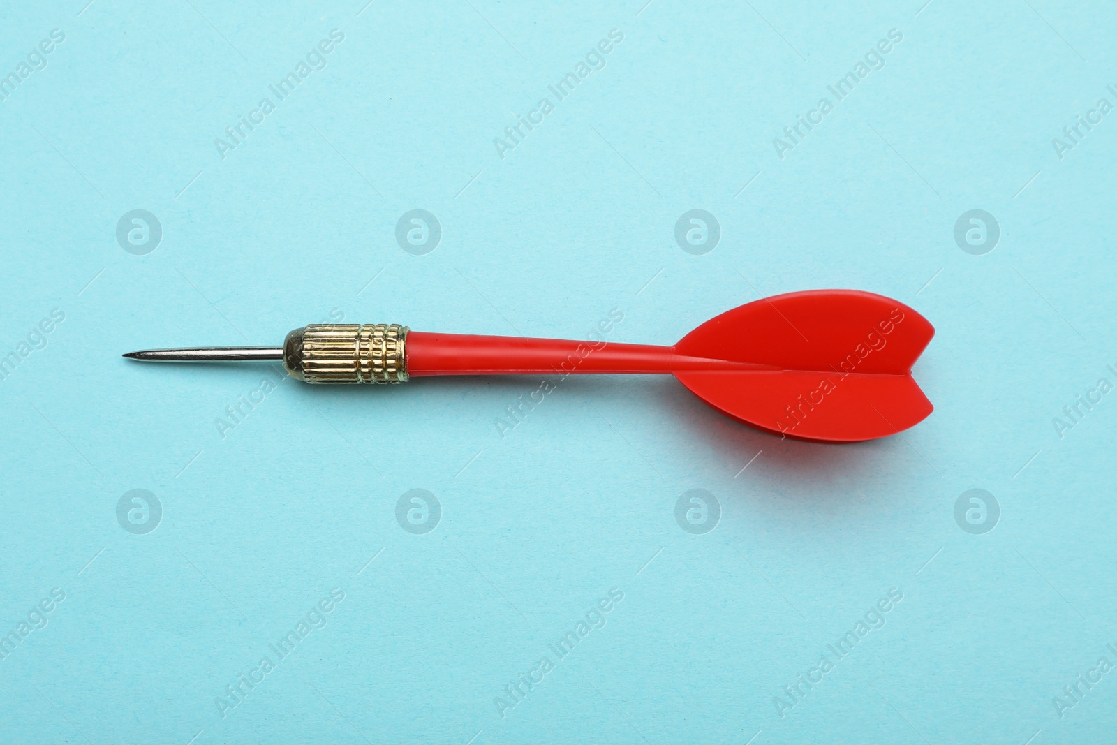 Photo of Red dart arrow on blue background, top view