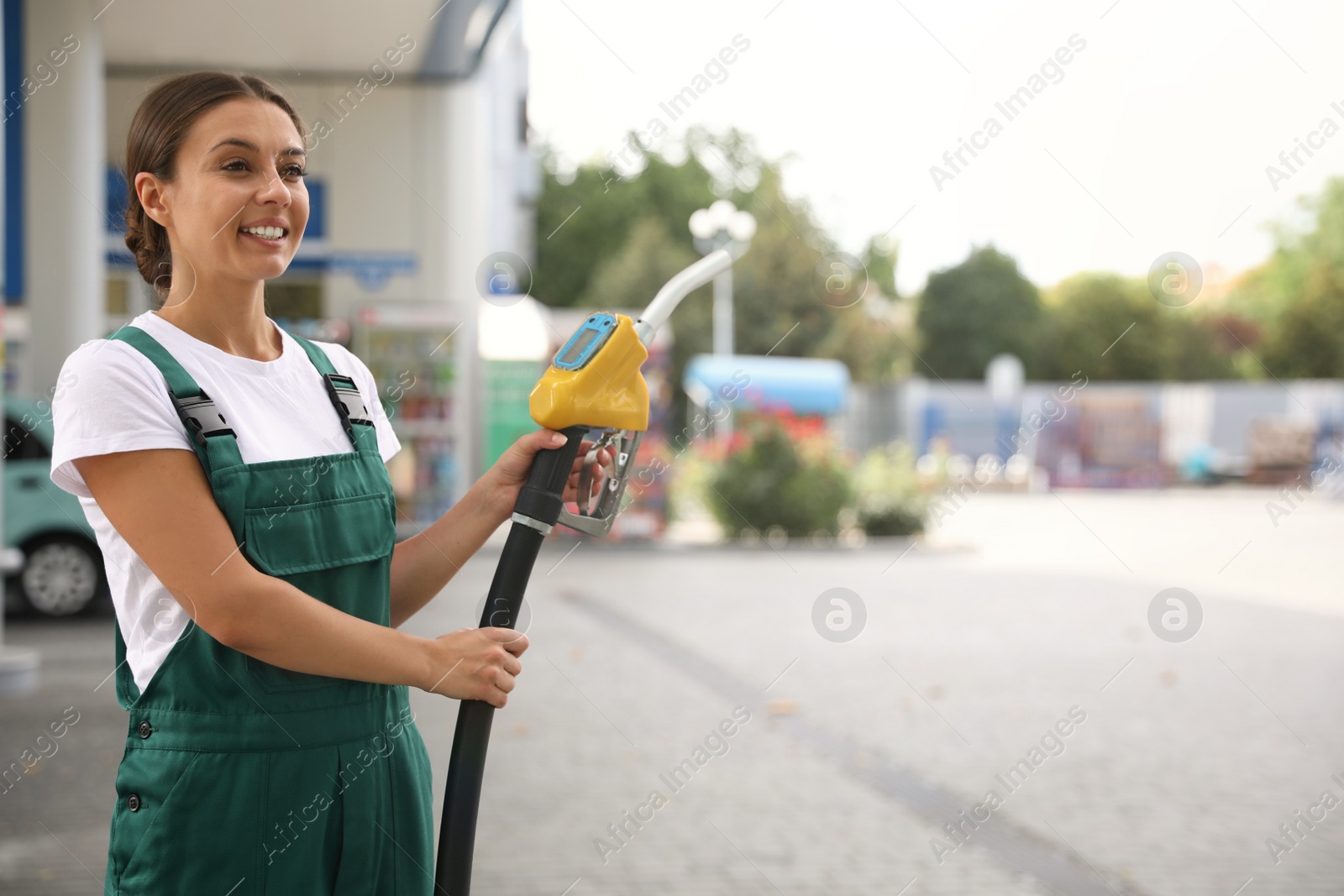 Photo of Young worker with fuel pump nozzle at modern gas station