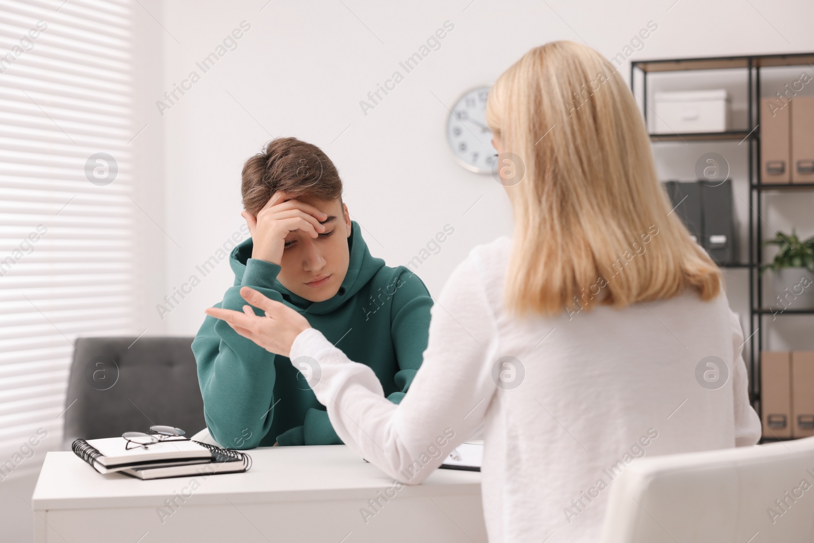 Photo of Psychologist working with teenage boy at table in office