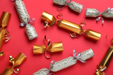 Photo of Bright Christmas crackers on red background, flat lay