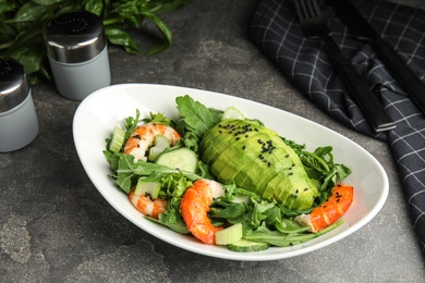 Photo of Delicious avocado salad with shrimps in bowl on grey table