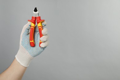 Photo of Man with diagonal pliers on grey background, closeup. Space for text