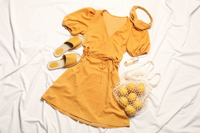 Flat lay composition with stylish yellow dress on white fabric