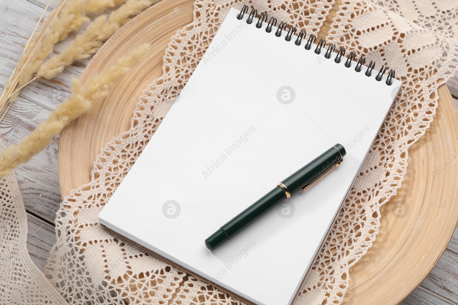 Photo of Guest list. Notebook, pen, spikelets and lace ribbon on wooden background, above view