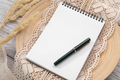 Guest list. Notebook, pen, spikelets and lace ribbon on wooden background, above view