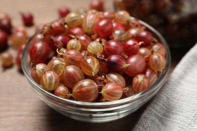 Bowl of fresh ripe gooseberries on wooden table, closeup