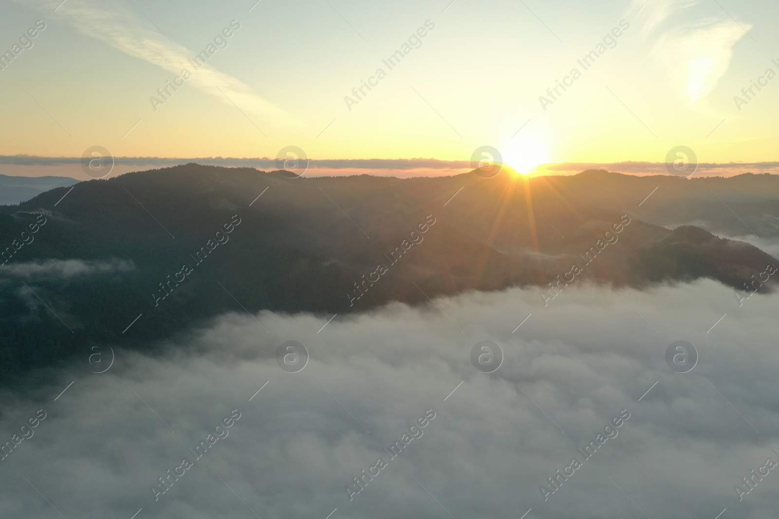 Photo of Aerial view of beautiful mountains covered with fluffy clouds at sunrise