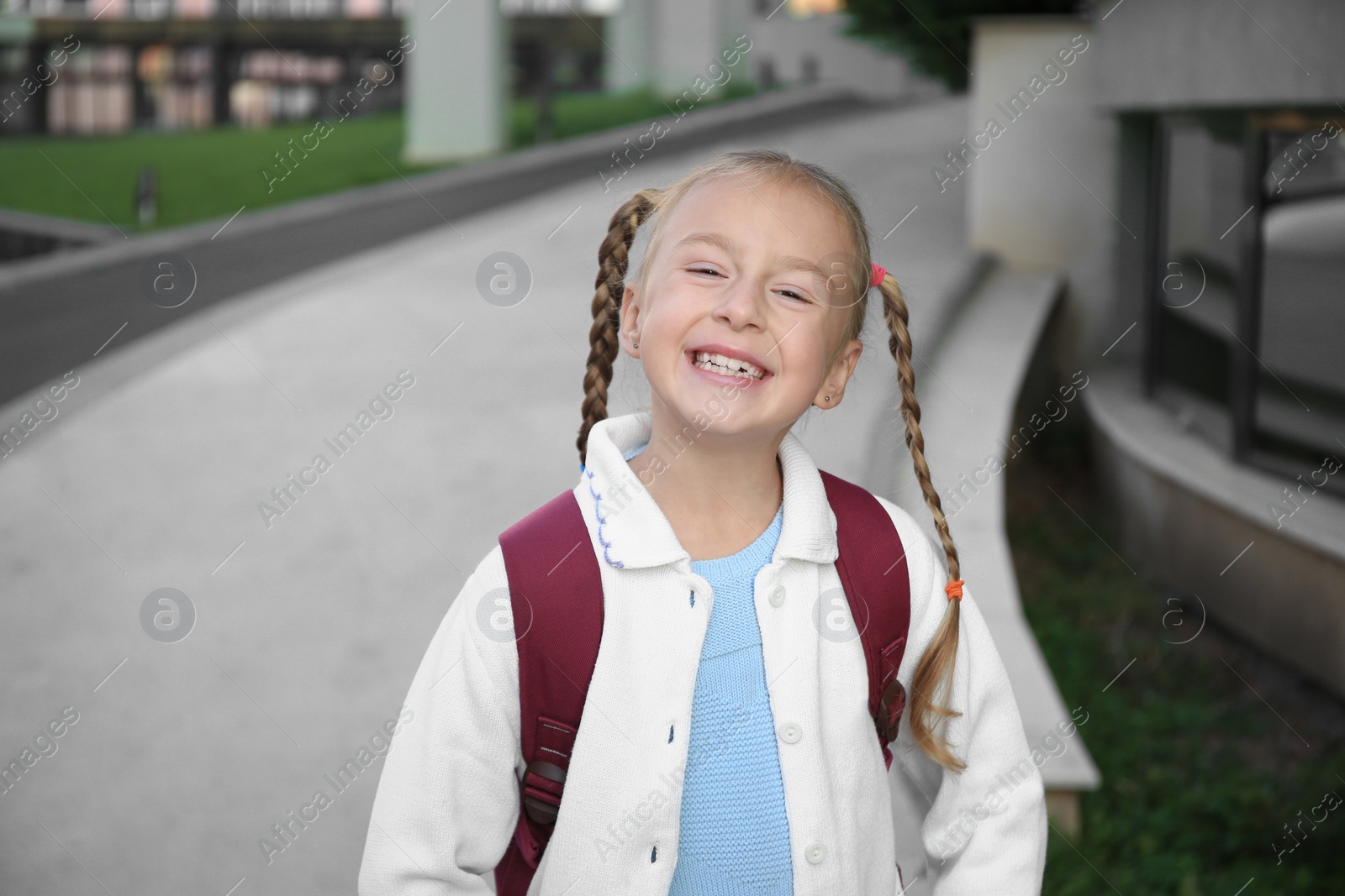 Photo of Cute little girl with backpack on city street