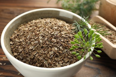 Photo of Bowl of dry seeds and fresh dill on table, closeup