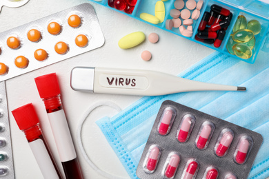 Photo of Thermometer with word VIRUS and medicines on white background, flat lay