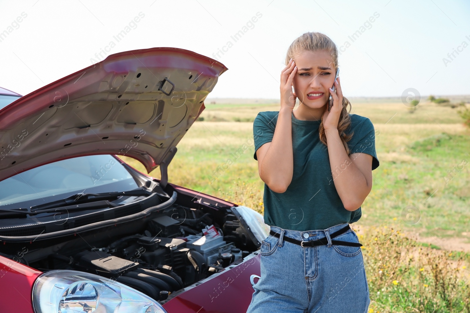 Photo of Woman talking on phone near broken car outdoors