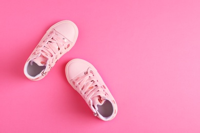 Photo of Pair of stylish child shoes on pink background, flat lay. Space for text