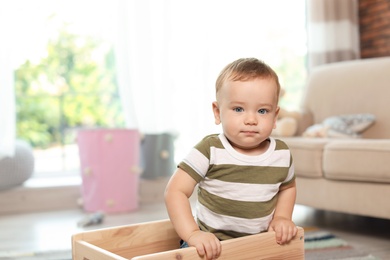 Photo of Adorable little baby in wooden cart at home