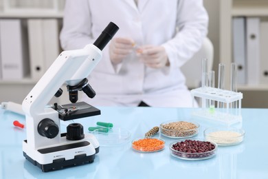 Photo of Quality control. Food inspector working in laboratory, focus on microscope and petri dishes with different products
