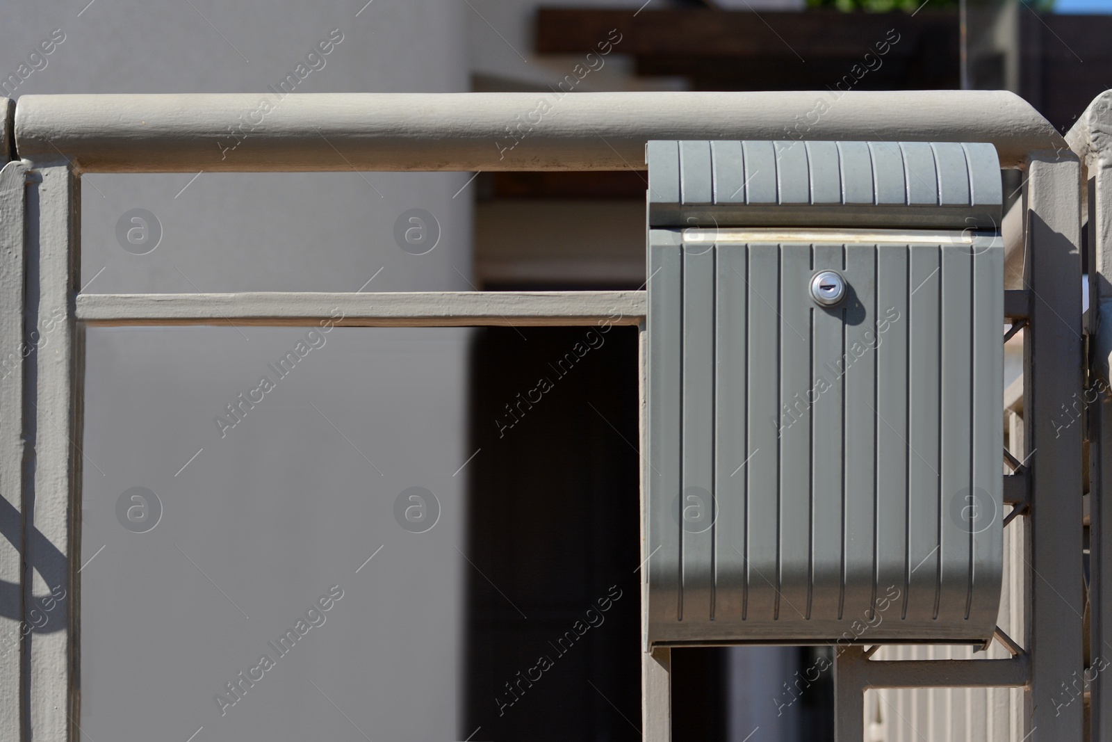 Photo of Beautiful metal letter box with plate on gate outdoors