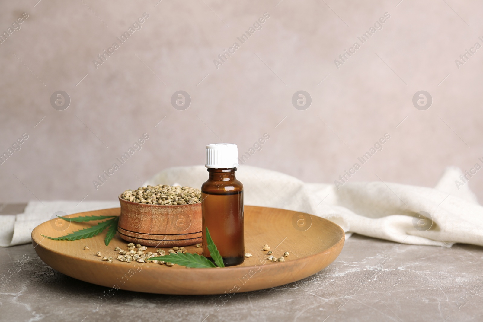 Photo of Plate with hemp seeds and bottle of extract on table