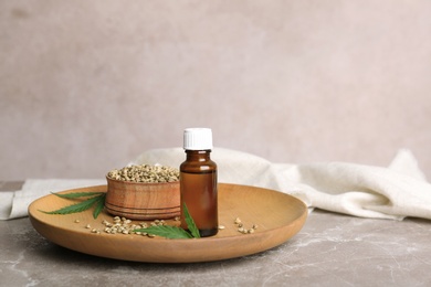 Plate with hemp seeds and bottle of extract on table