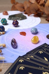 Photo of Zodiac wheel, tarot cards, astrology dices and gemstones on table, selective focus