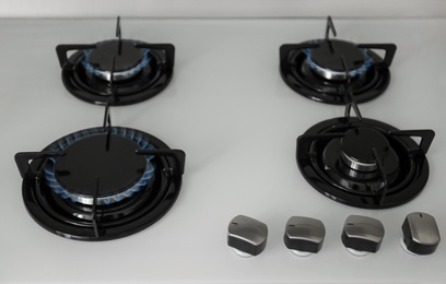 Photo of Gas burners with blue flame on modern stove