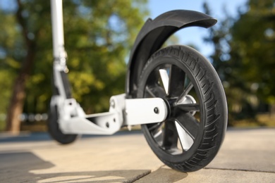 Photo of Modern kick scooter outdoors on sunny day, closeup