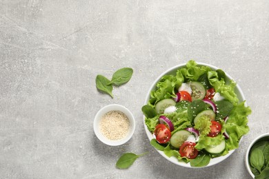 Delicious salad in bowl on light grey table, flat lay. Space for text