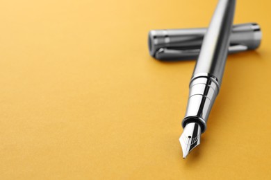 Photo of Stylish fountain pen with cap on yellow background, closeup. Space for text