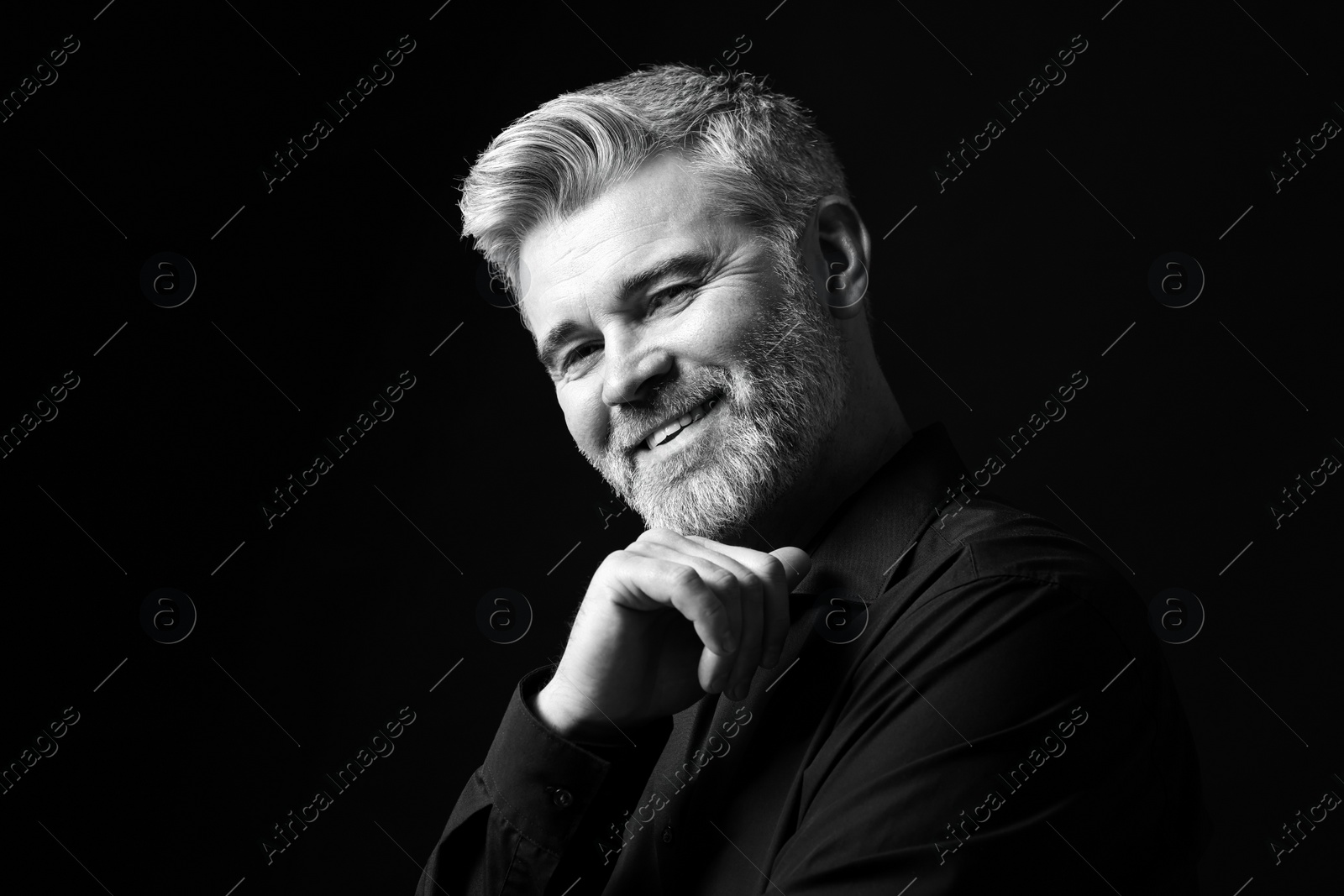 Photo of Portrait of smiling man on dark background. Black and white effect