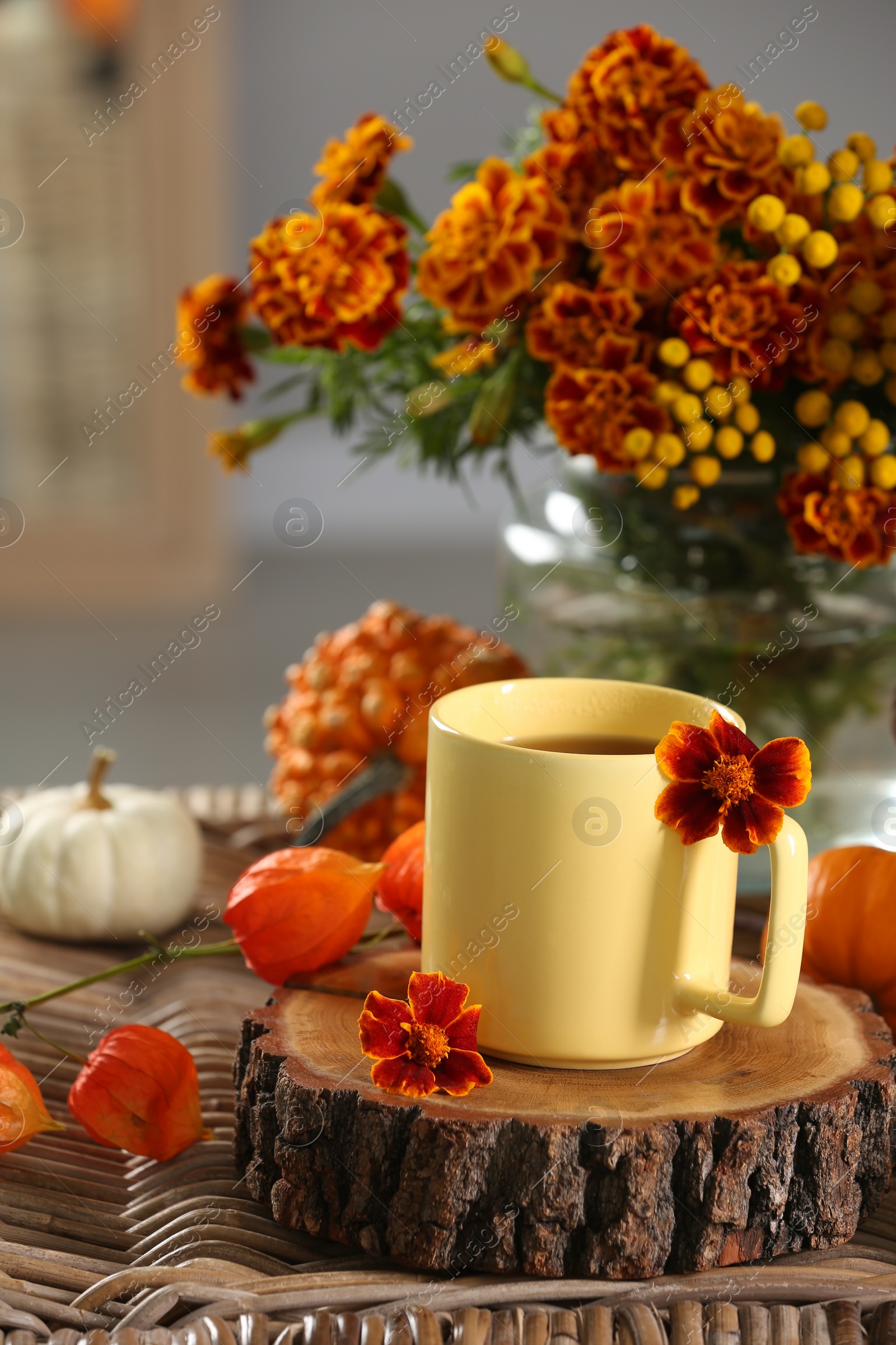 Photo of Cup of drink and autumn flowers on wicker table