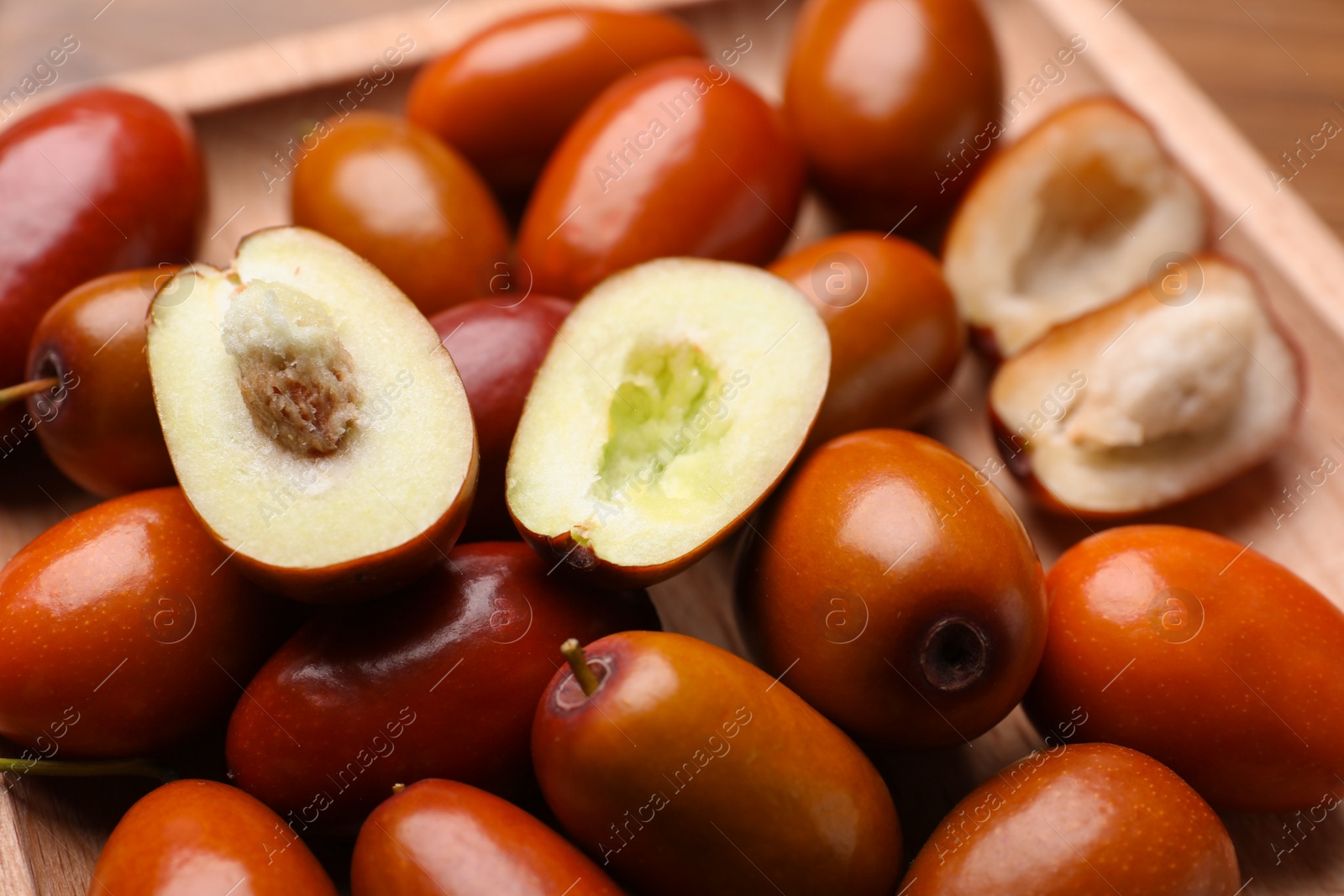 Photo of Fresh Ziziphus jujuba fruits on wooden plate, closeup