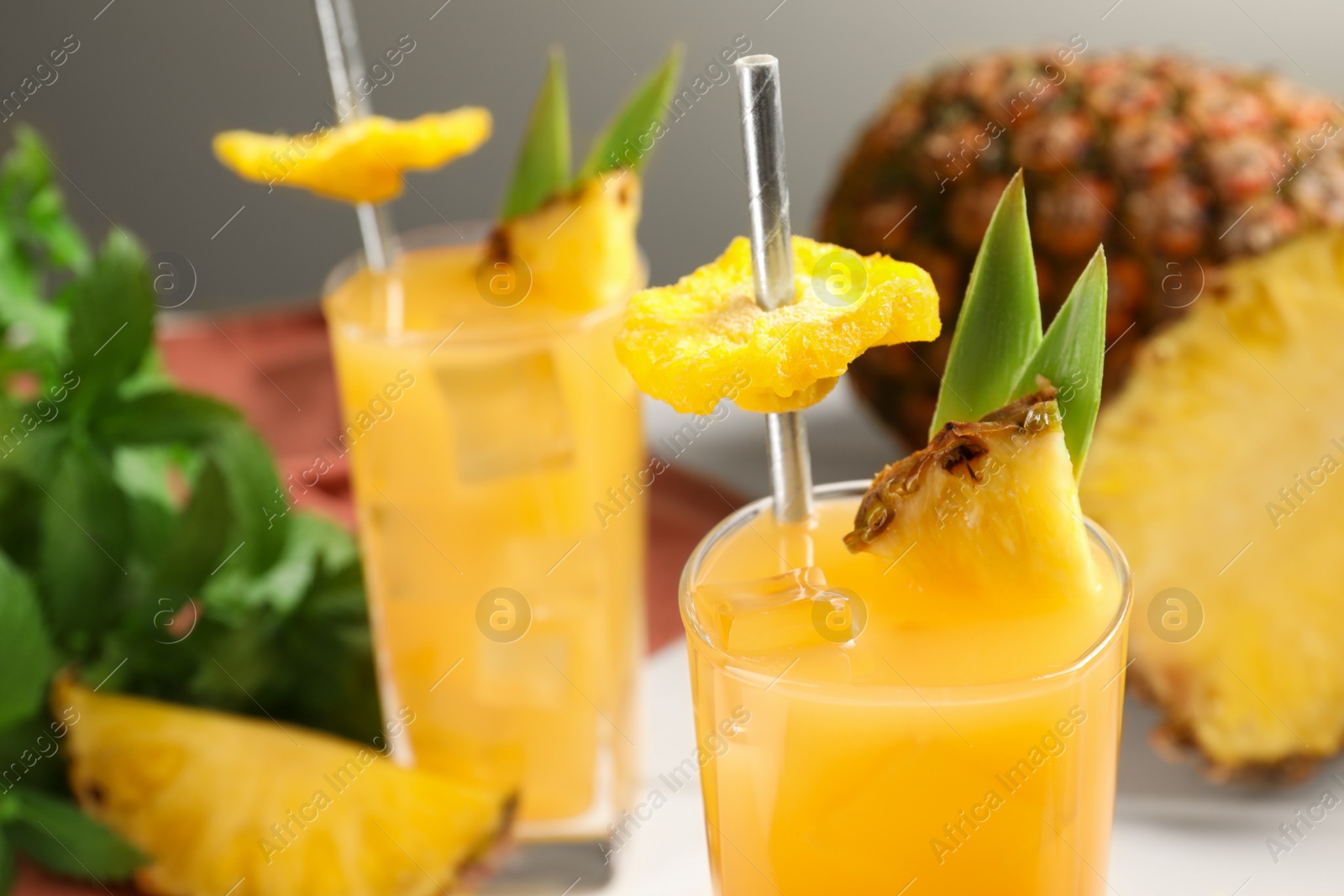 Photo of Tasty pineapple cocktail and sliced fruit on table, closeup