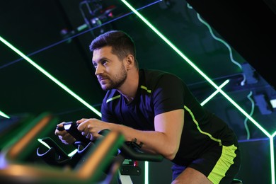 Man training on exercise bike in fitness club