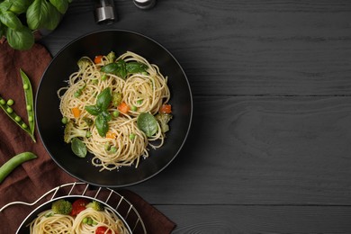 Delicious pasta primavera with basil, broccoli and peas served on grey wooden table, flat lay. Space for text
