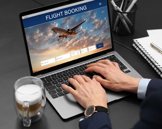 Image of Woman using laptop to book flight at black table, closeup
